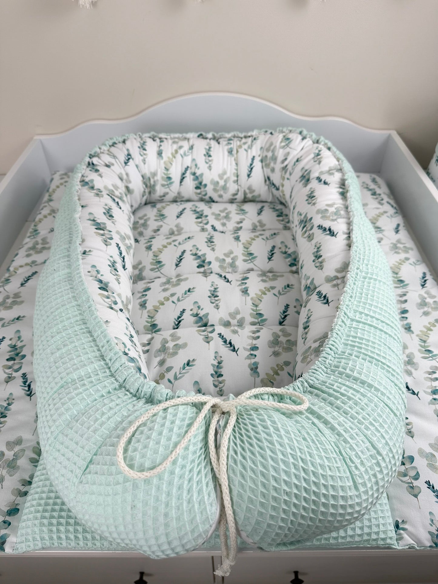 as Nestchen ist aus atmungsaktiven Materialien gefertigt und hat eine gepolsterte Umrandung, die das Baby sanft umschließt und vor äußeren Störungen schützt. Ideal für den Einsatz im Kinderbett oder auf der Couch, um dem Baby einen ruhigen und geschützten Schlafplatz zu bieten.