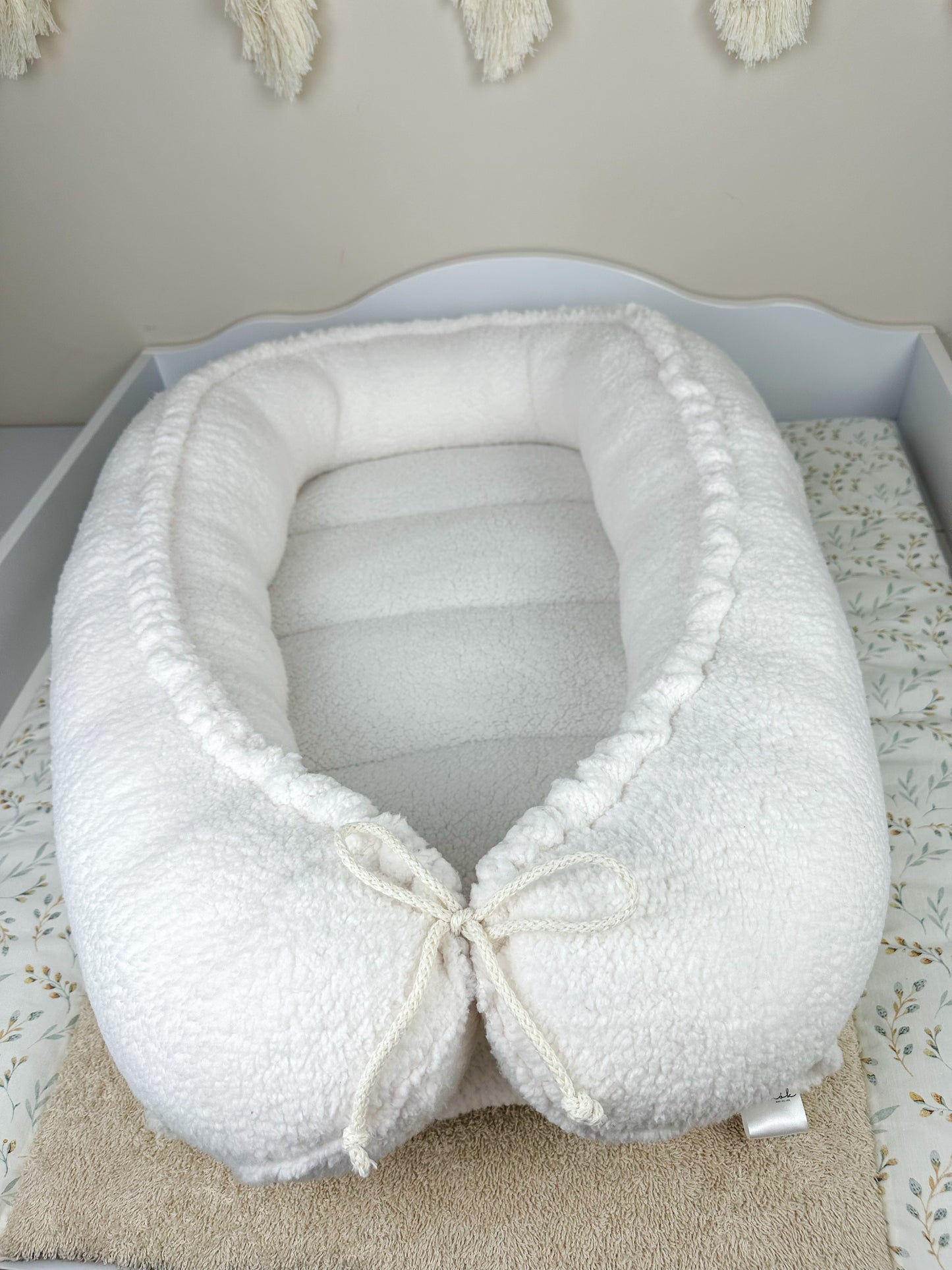 as Nestchen ist aus atmungsaktiven Materialien gefertigt und hat eine gepolsterte Umrandung, die das Baby sanft umschließt und vor äußeren Störungen schützt. Ideal für den Einsatz im Kinderbett oder auf der Couch, um dem Baby einen ruhigen und geschützten Schlafplatz zu bieten.