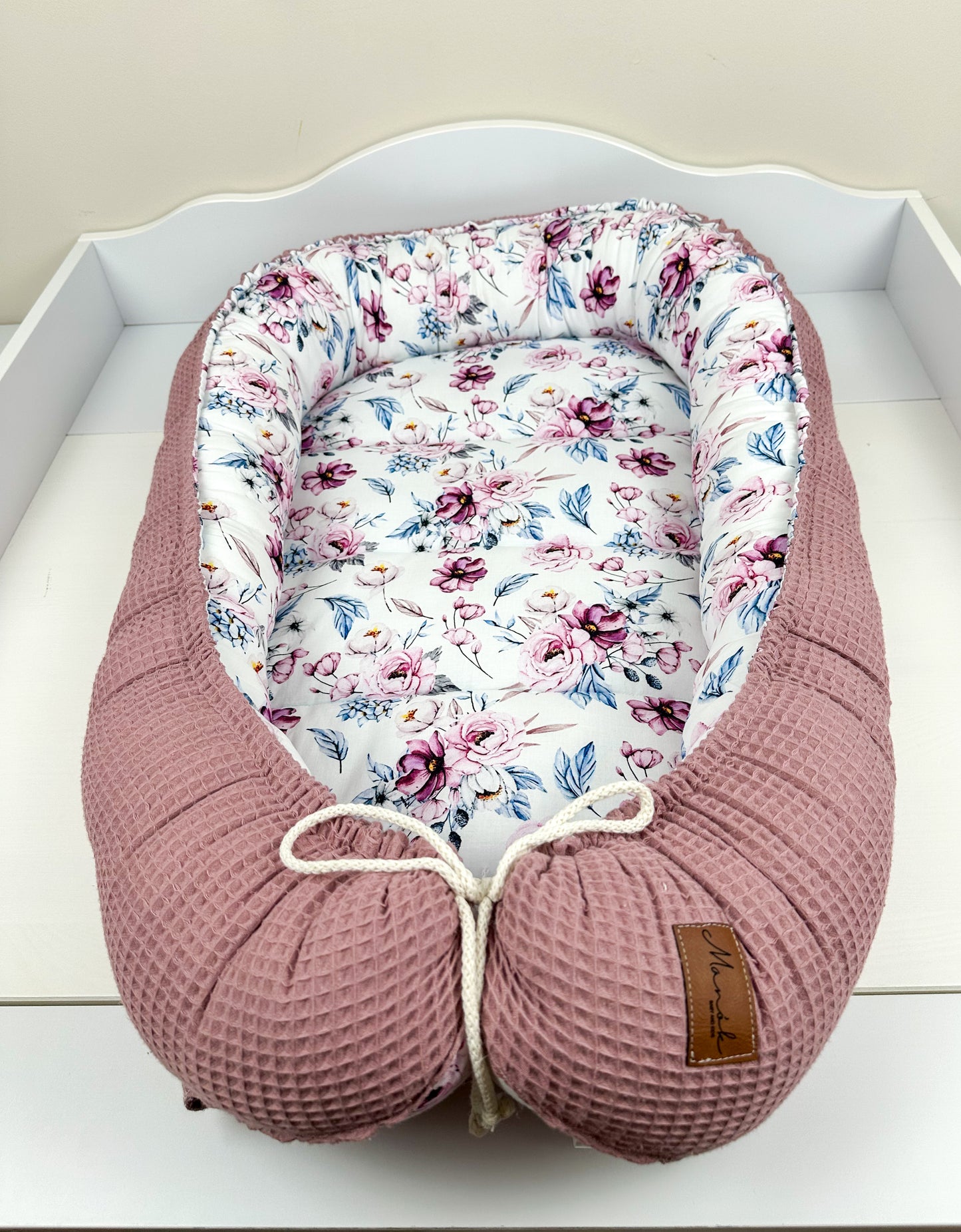 as Nestchen ist aus atmungsaktiven Materialien gefertigt und hat eine gepolsterte Umrandung, die das Baby sanft umschließt und vor äußeren Störungen schützt. Ideal für den Einsatz im Kinderbett oder auf der Couch, um dem Baby einen ruhigen und geschützten Schlafplatz zu bieten.