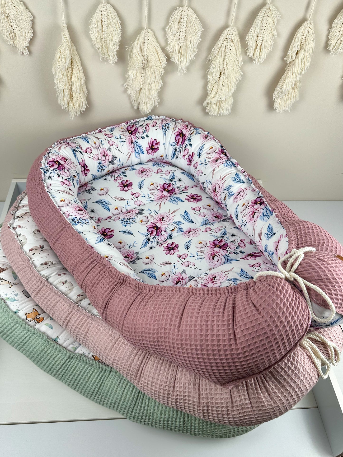 as Nestchen ist aus atmungsaktiven Materialien gefertigt und hat eine gepolsterte Umrandung, die das Baby sanft umschließt und vor äußeren Störungen schützt. Ideal für den Einsatz im Kinderbett oder auf der Couch, um dem Baby einen ruhigen und geschützten Schlafplatz zu bieten.
