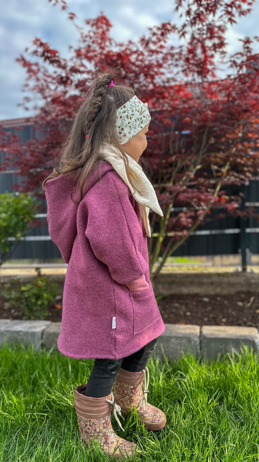 Person trägt eine Walkjacke aus Wollstoff kombiniert mit einem leichten, luftigen Musselintuch um den Hals.
