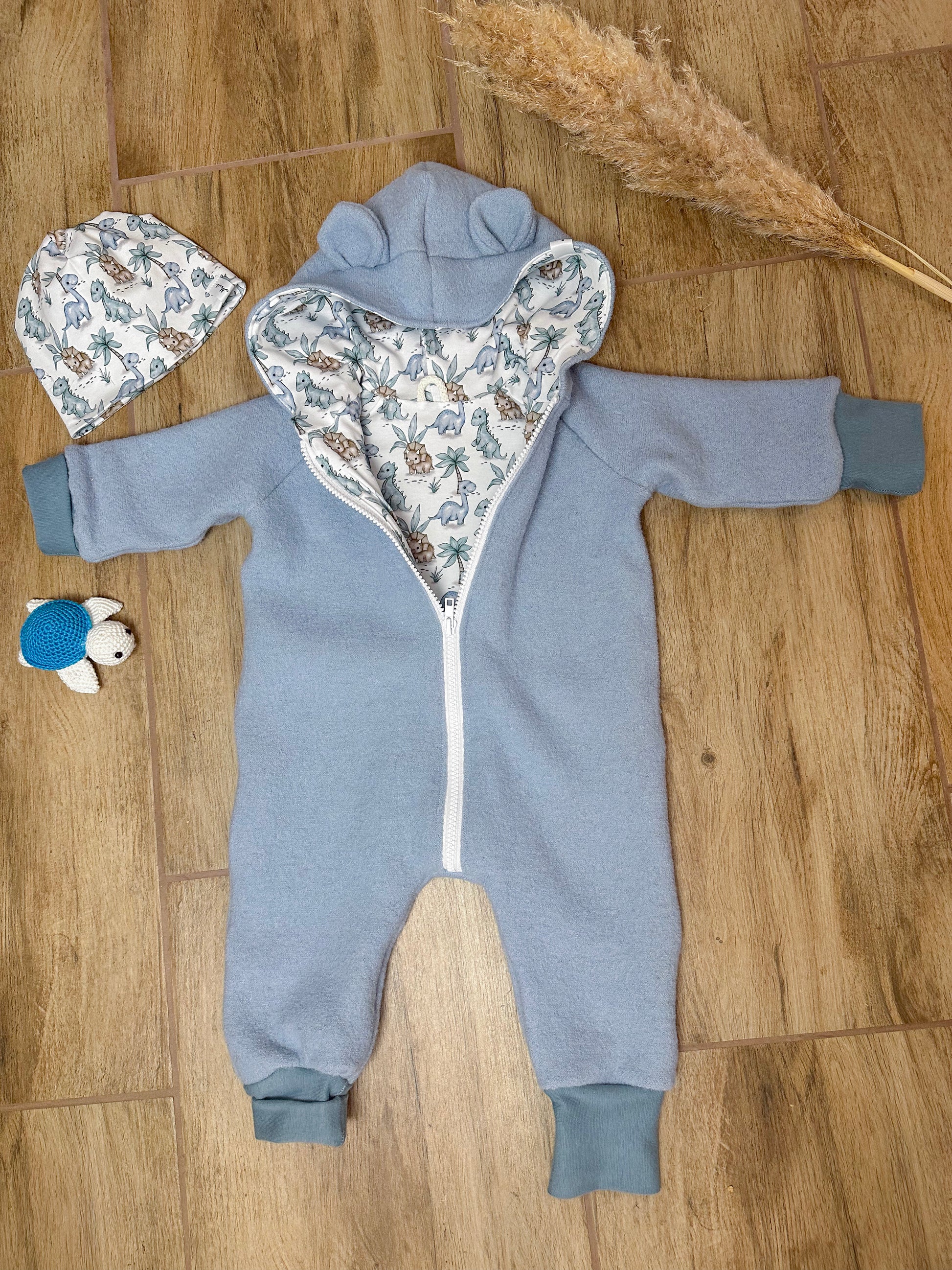 Ein Walkoverall für Babys ist ein warmer und bequemer Anzug, der aus Walkstoff gefertigt ist. Dieser Stoff ist besonders gut geeignet, um die Kleinen warm zu halten, da er atmungsaktiv und gleichzeitig isolierend ist. Walkoveralls sind oft handgemacht, was bedeutet, dass sie mit viel Liebe und Sorgfalt gefertigt werden. Sie sind ideal für kalte Tage, da sie den ganzen Körper des Babys warmhalten und gleichzeitig Bewegungsfreiheit bieten. Viele Modelle haben praktische Details wie eine Kapuze, um den Kopf de